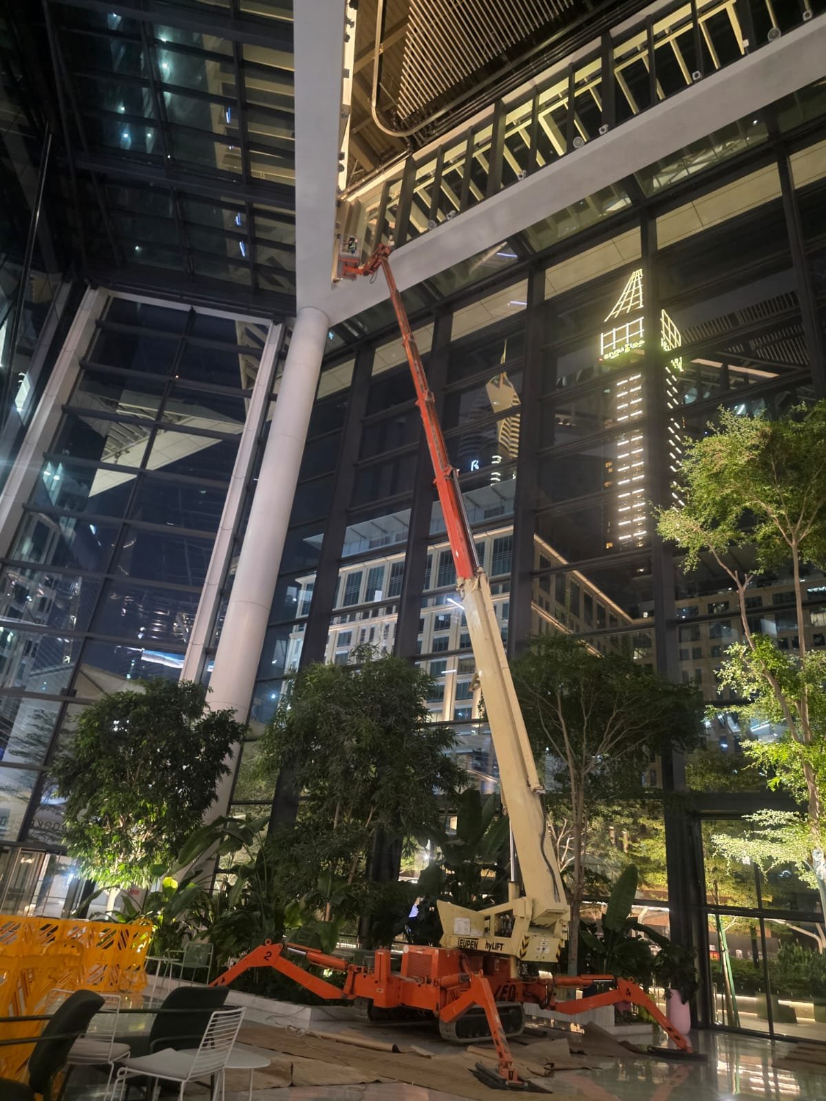 Spider lift reaching high inside a glass atrium for ceiling maintenance
